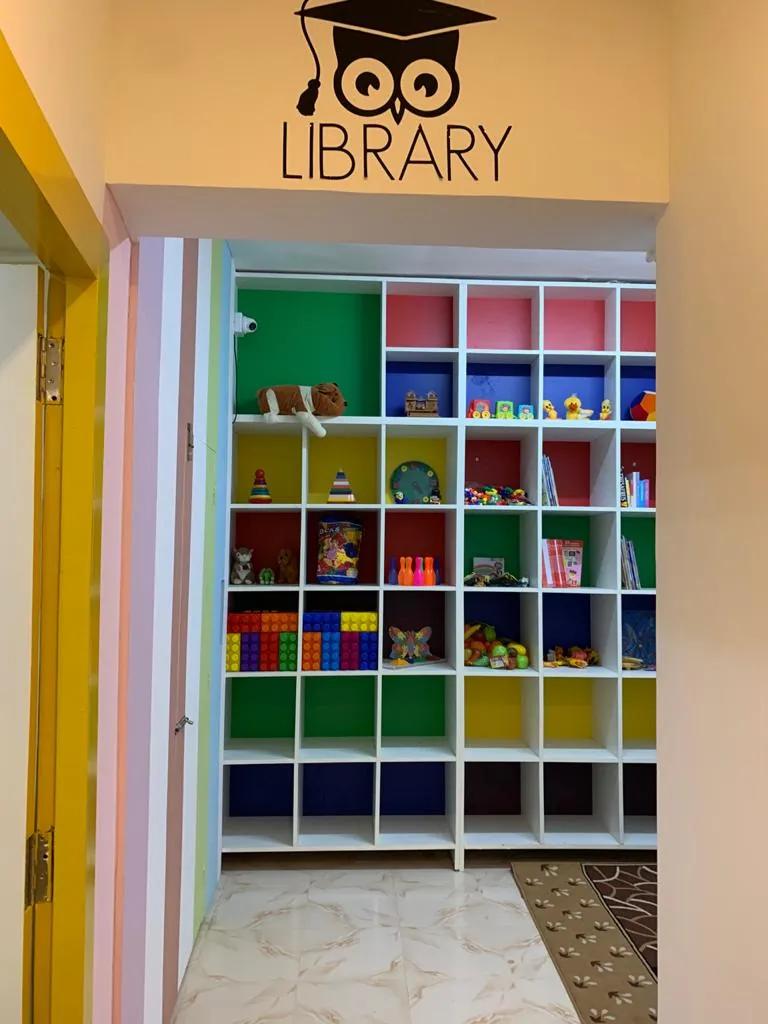 A library corner with a Library sign above open shelves of colourful bins